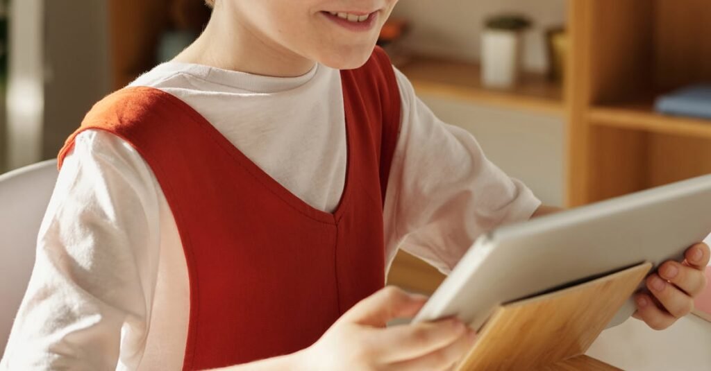 A happy child using a tablet for online education at home during the day.