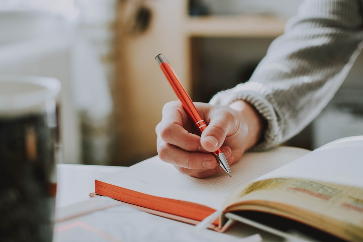 Student writing Japanese grammar practice sentences in a notebook